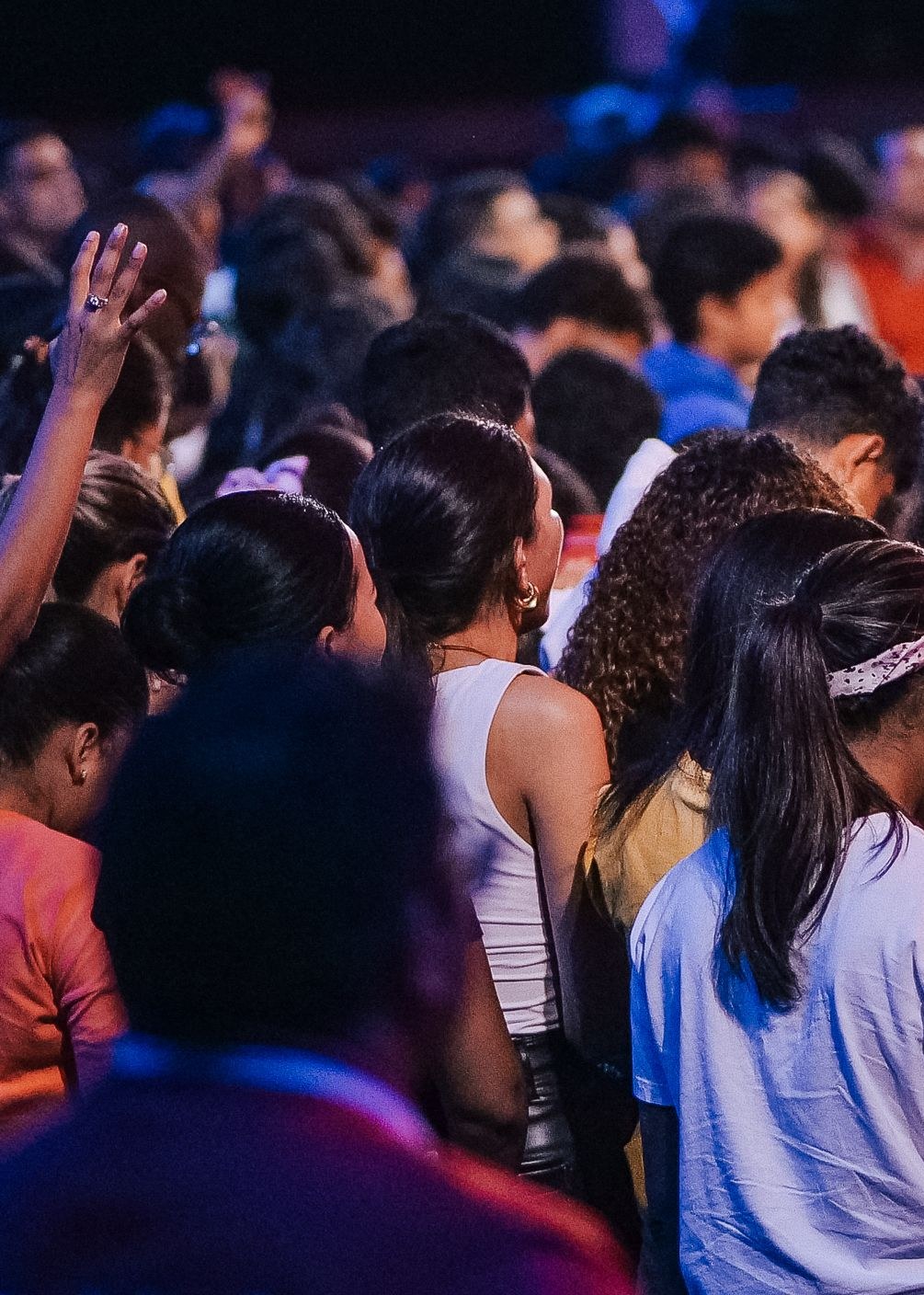 A congregation standing close together with hands raised during worship